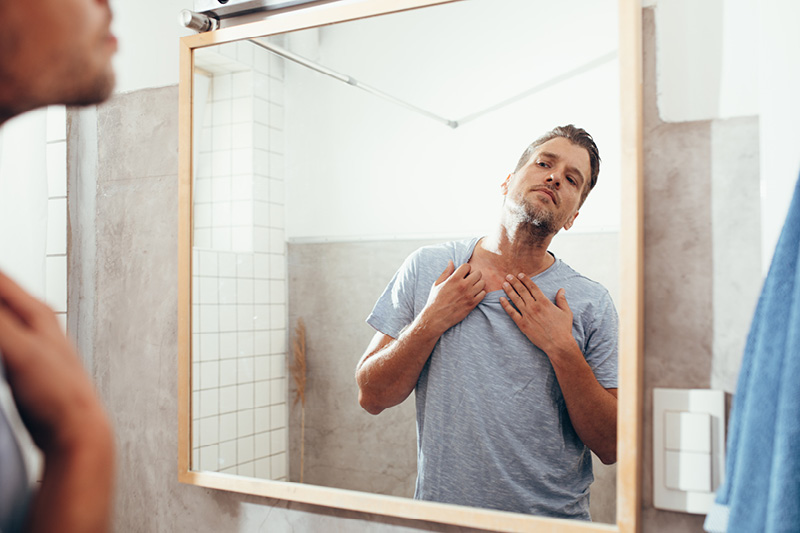 Man examining his neck in the mirror