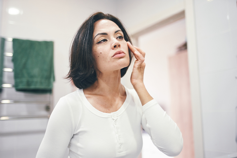 Women examining her face in the mirror