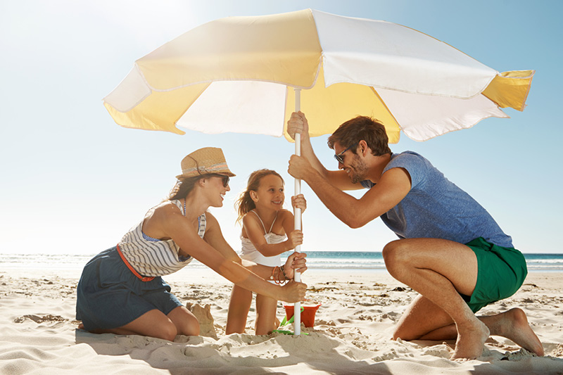 Family at the beach, sitting under an umbrella