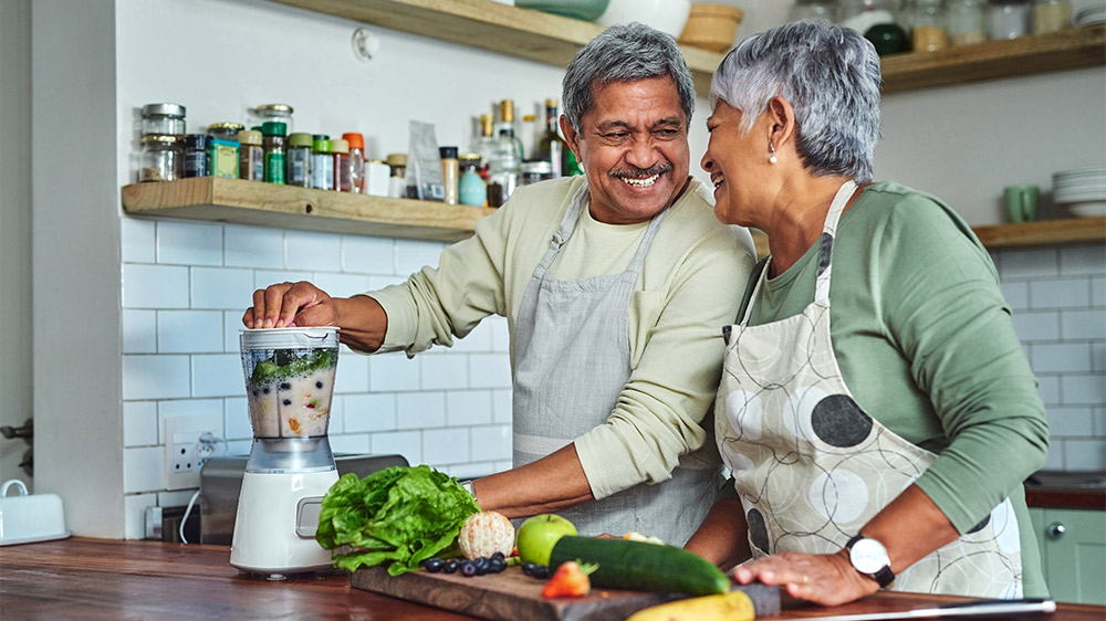 older adult couple making smoothies