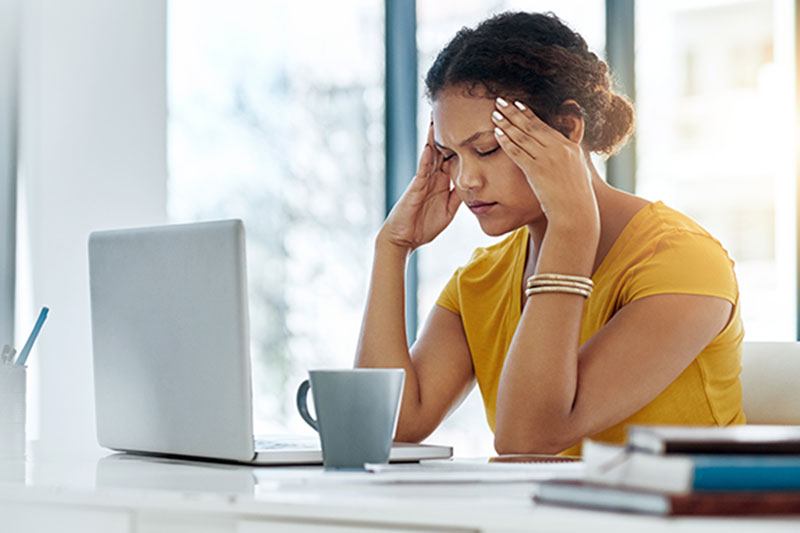 Woman at computer fighting a headache.